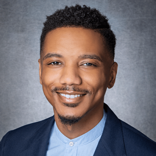 a man wearing a suit and tie smiling at the camera