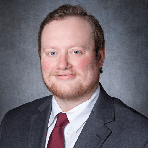 a man wearing a suit and tie smiling at the camera